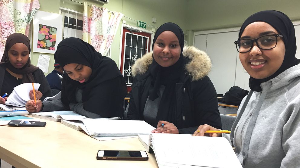 Fyra gymnasieelever sitter på en rad och pluggar.