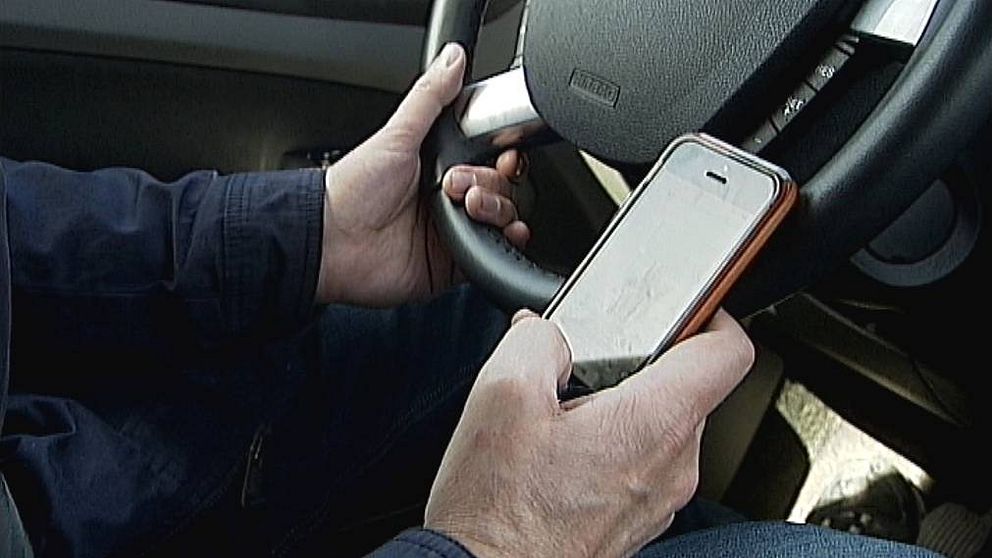 manshänder som håller i ratten i bil och i en mobil