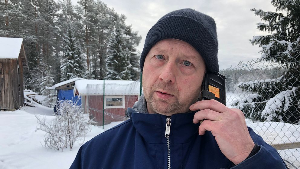 en man som pratar i mobilen, utomhus på snöig gård