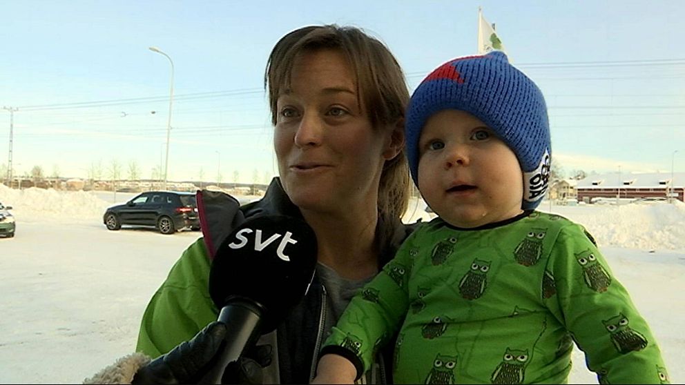 en kvinna med liten pojke i famnen intervjuas ute vintertid