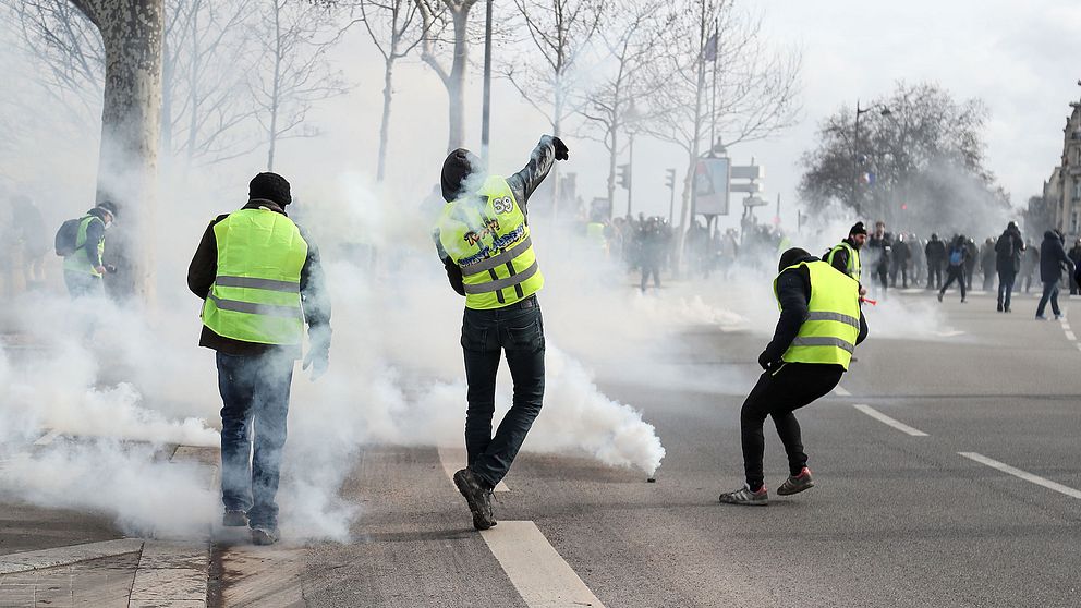 Demonstranter från Gula Västarna i Paris kastar tillbaka tårgasgranater som polisen skjutit