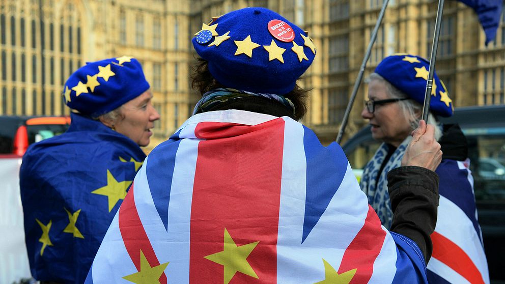 Brexitmotståndare viftar med flaggor utanför parlamentet i London.