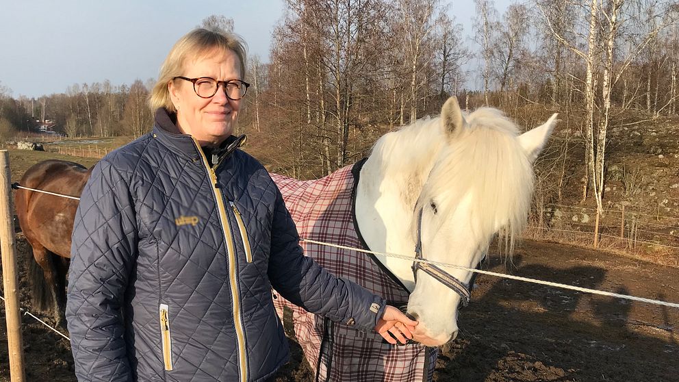Annette Karlsson klappar en av ridskolans hästar på mulen.