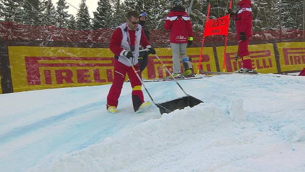 man i rödvita kläder skottar snö i skidbacke i Åre under alpina VM 2019