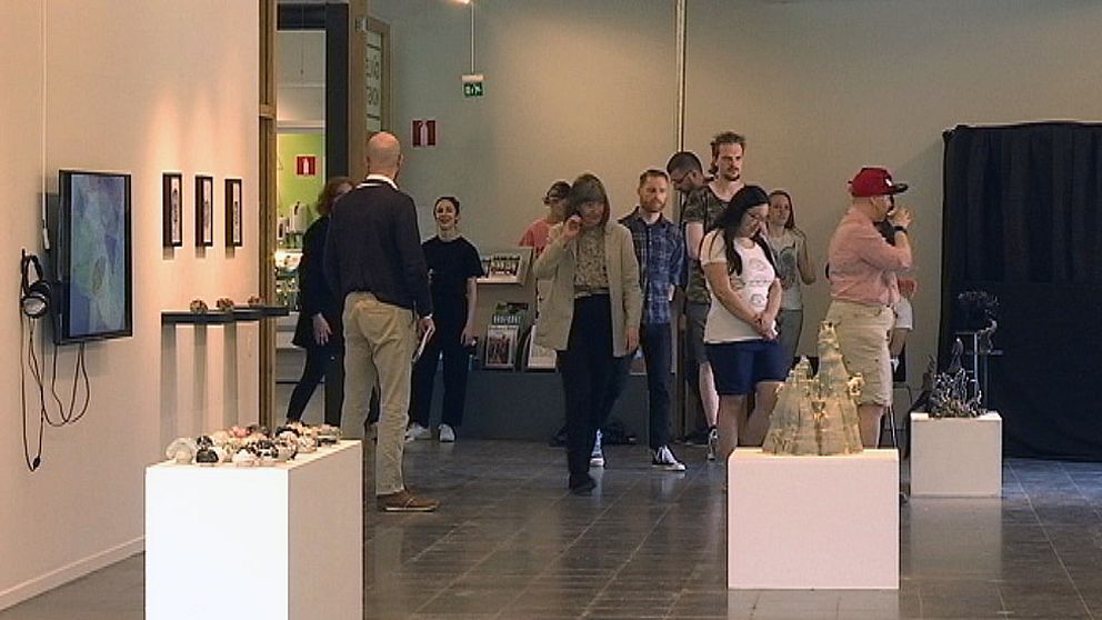 Personer i utställningshall. Flera konstverk (Statyer) i förgrunden