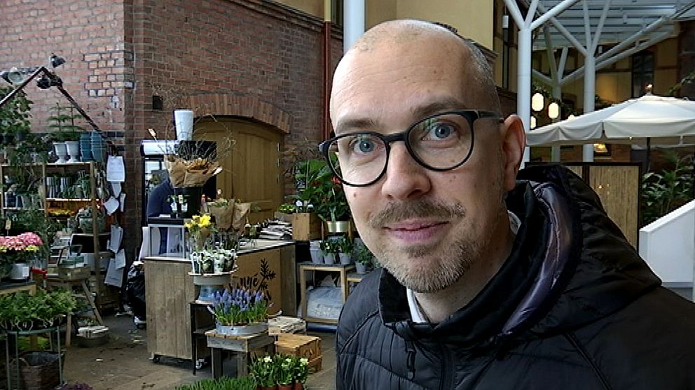 En man med glasögon vid en blomsteraffär