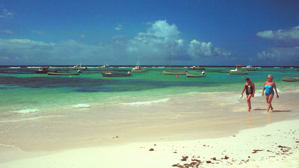 Två kvinnor går på en strand på Barbados.