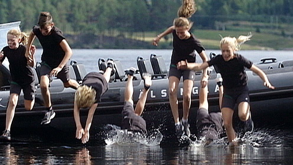 Flera barn som hoppar ner i vattnet från en stor gummibåt