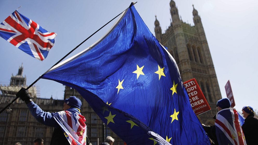 Personer som viftar med brittiska flaggan och europeiska unionens flagga utanför parlamentet.