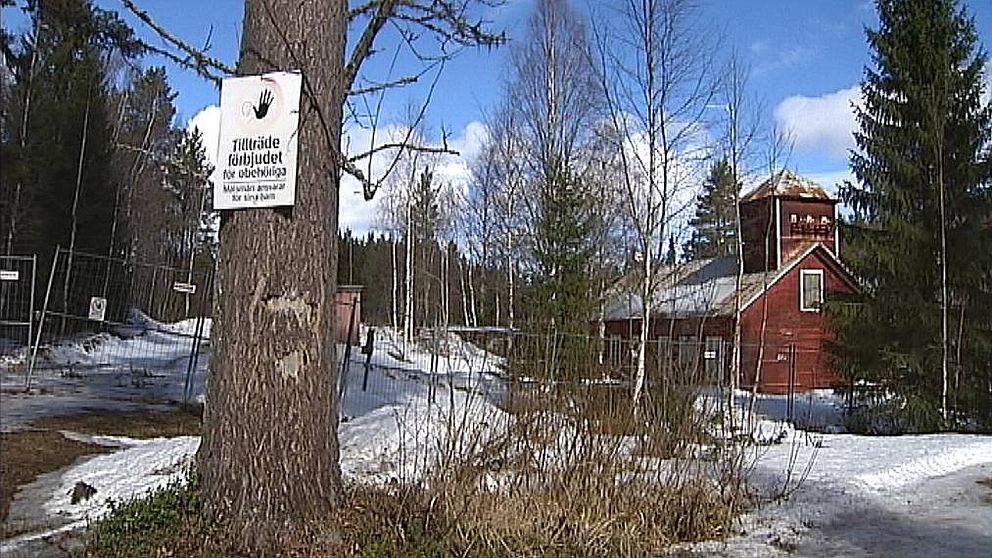 arkivbild på Långforsens kraftverk i Långan. Skylt med tillsträde förbjudet i förgrunden och en en gammal faluröd träbyggnad i bakgrunden