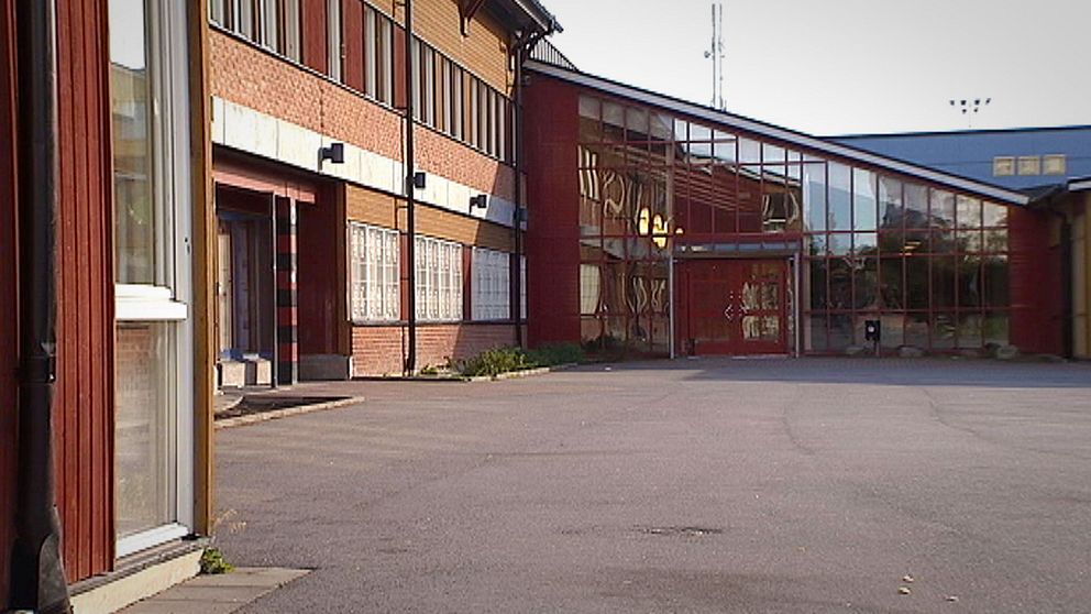 Exteriör bild på Vivallaskolan med asfaltsplan framför.