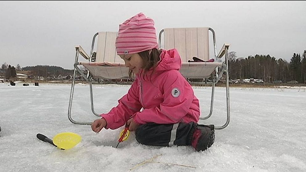 Flicka sitter och pimplar på is i Mårdsjön