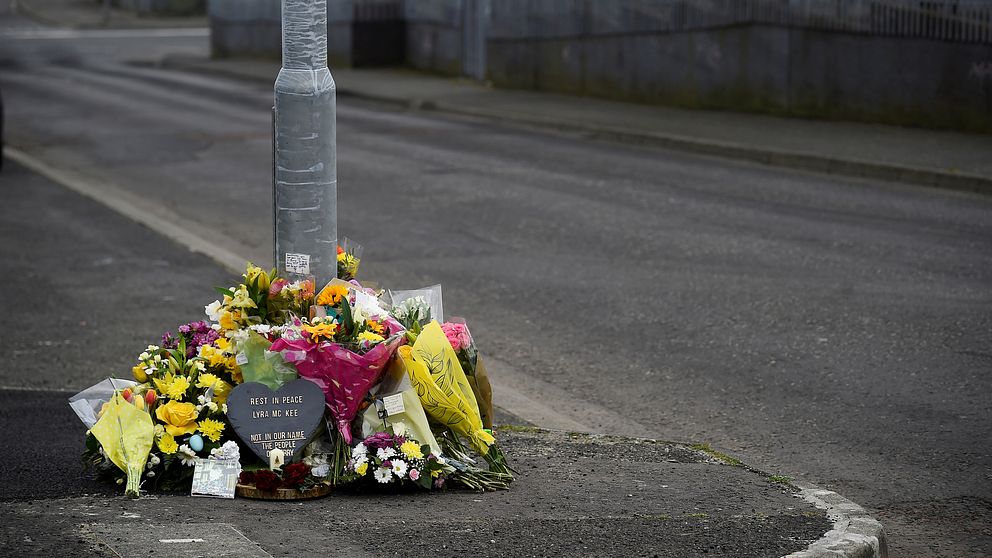 Blommor på asfalterad gata vid en lyktstolpe.