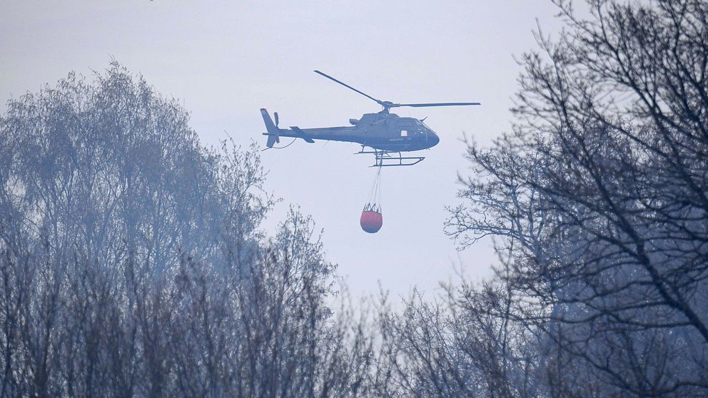 En helikopter vattenbombar brand i Hässleholms kommun den 24 april 2019.