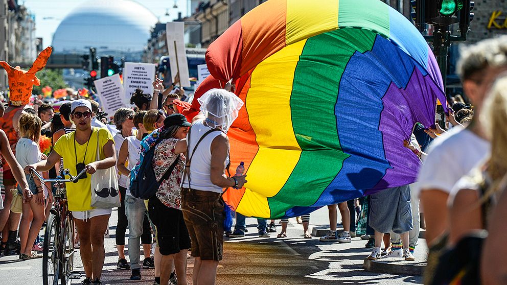 Regnbågsflaggan bärs längs Götgatan med Globen i bakgrunden under Pridefestivalen i Stockholm 2013.