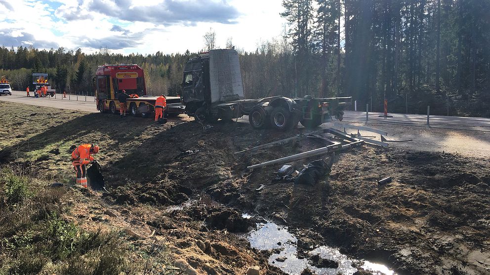 bärgningsbil och lastbil samt personal, lerigt dike i förgrund