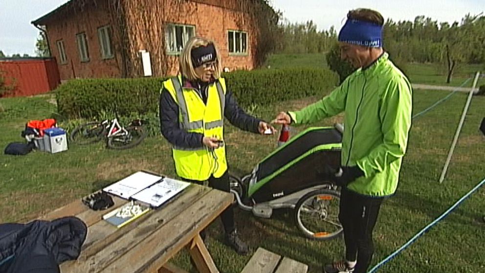 Volonär i Örebro tar emot löpare (med barnvagn) som kommit i mål och registrerar tiden.
