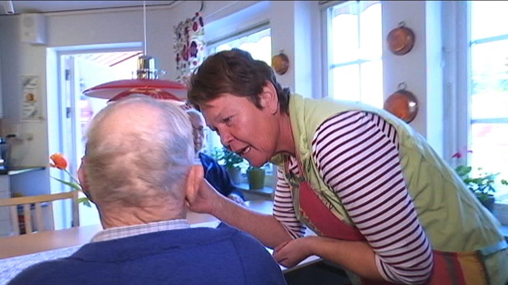 Kökspersonalen stoppar in i en sked i munnen på en äldre man som får smaka av maten som lagas.