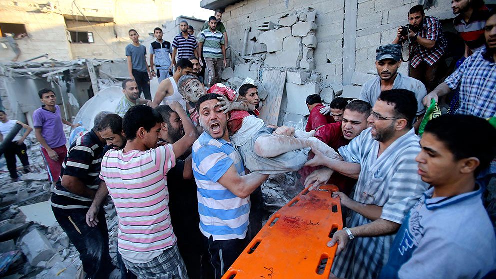 Palestinier bär en skadad pojke som evakuerades från en byggnad som försötrdes i en israelisk flygattack tidigt på söndagsmorgonen. Minst 30 personer uppges ha dödats på söndagen.