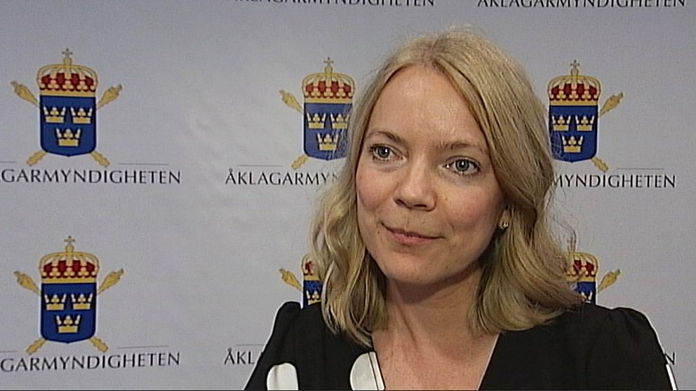 Åklagaren Anna Asklöf framför en vägg med Åklagarmyndighetens logotyp.