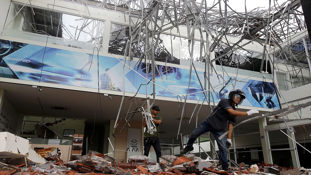 Två män röjer bråte efter en jordbävning.