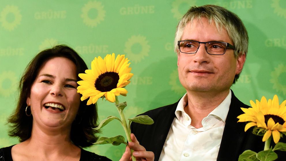 Anna Baerbock och Sven Giegold är fglada och håller upp solrosor.