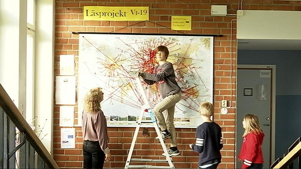 Karta med röda streck. Elever på Stallarholmsskolan i Strängnäs. Pojke klättrar upp för stege. Lärare tittar på elev och karta.