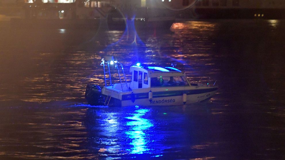 En polisbåt letar efter överlevande i det mörka vattnet efter olyckan.