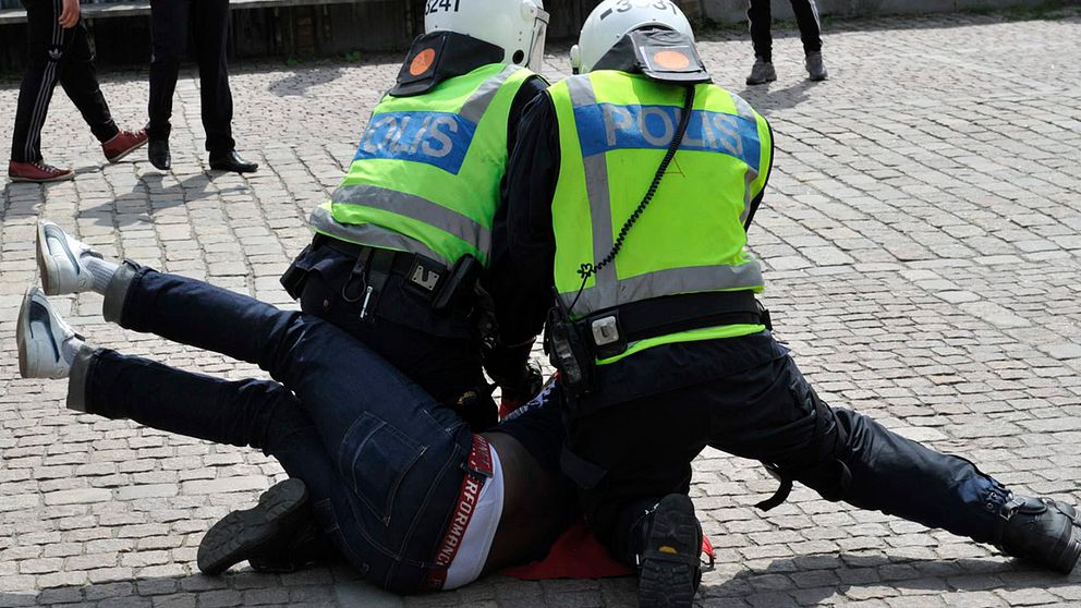 Två polis håller ner en demonstrant.