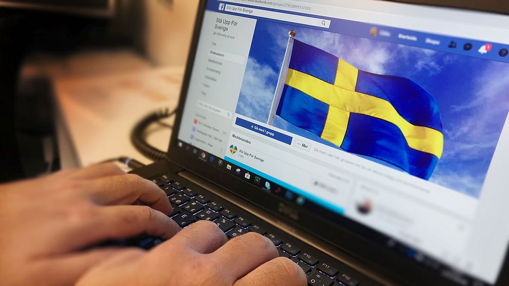 En person skriver på sin laptop. På skärmen syns svenska flaggan som används som bakgrundsbild i Stå upp för Sverige-gruppen på Facebook.