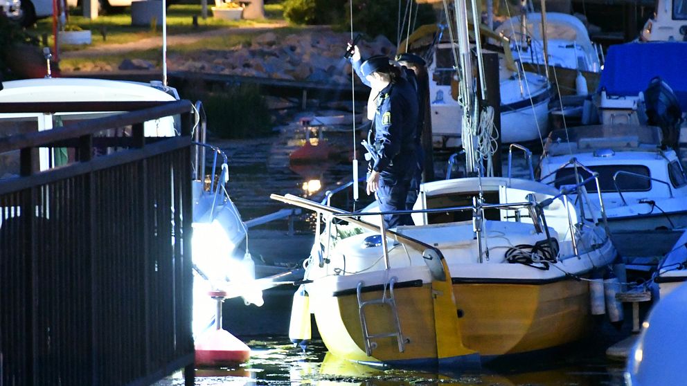 Två poliser står på en båt och lyser med ficklampor mot vattnet.