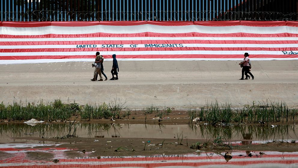 Människor går vid gränsen mellan USA och Mexiko.