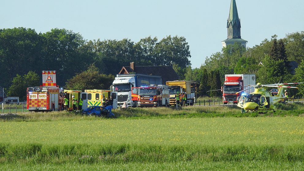 Ambulanshelikopter och brandbilar bredvid en avstängd väg.