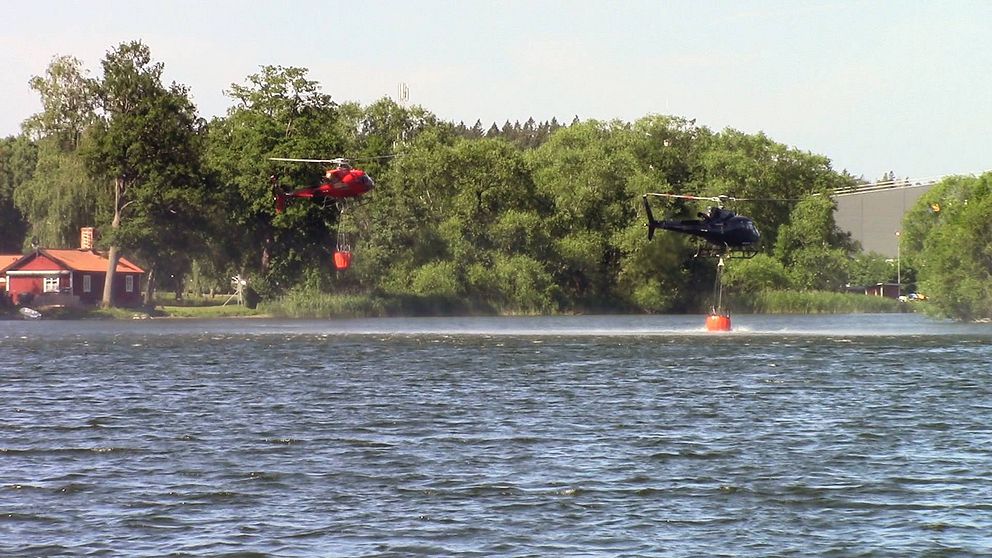 Helikoptrar hämtar vatten från Norrviken för att vattenbomba brand på Järvafältet.