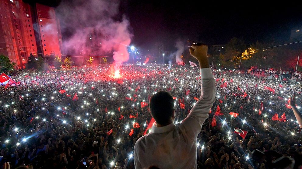 Ekrem Imamoğlu står framför ett folkhav med turkiska flaggor.