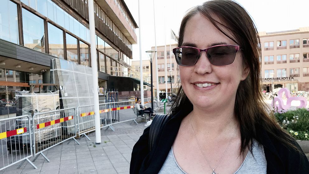 Sandra Johansson står på Olof Palmes torg i Örebro. Hon är iförd solglasögon, grått linne och svart kofta.