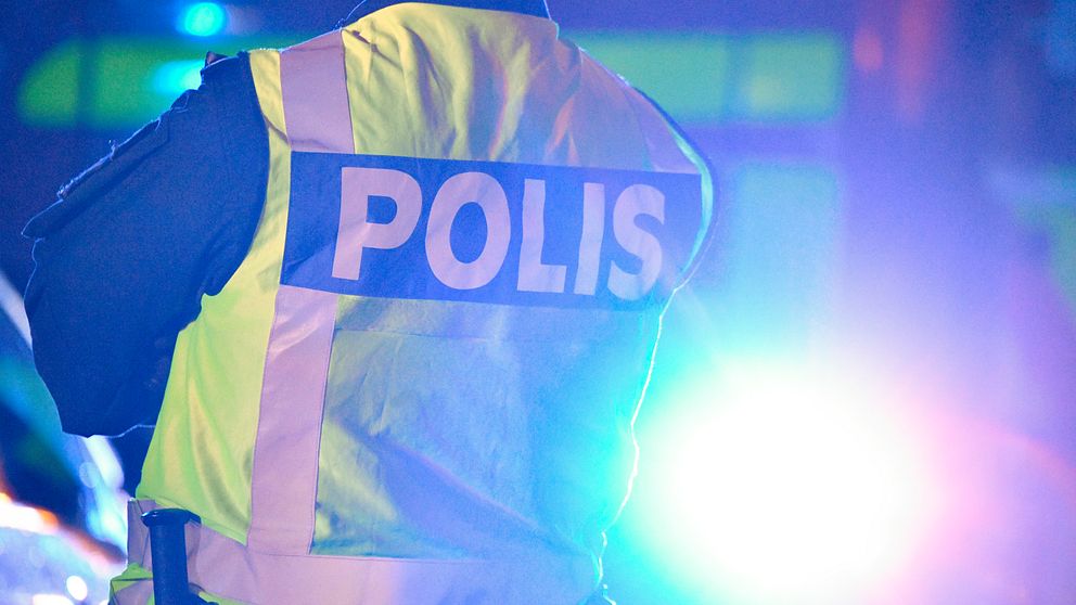 polis med ryggen mot kameran i motljus