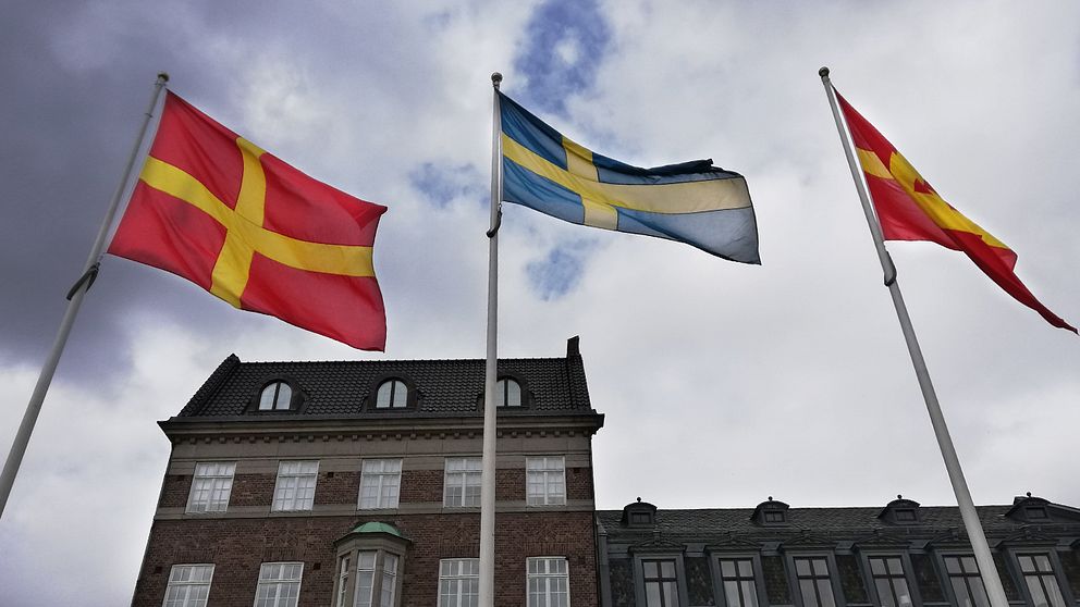 Två skånska rödgula flaggor vajar på varsin sida om den svenska flaggan på Stortorget i Lund, då det under dagen firades Skåneländska flaggans dag.