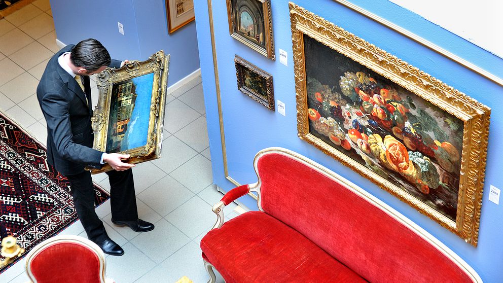 En man granskar en tavla på Stockholms auktionsverk.