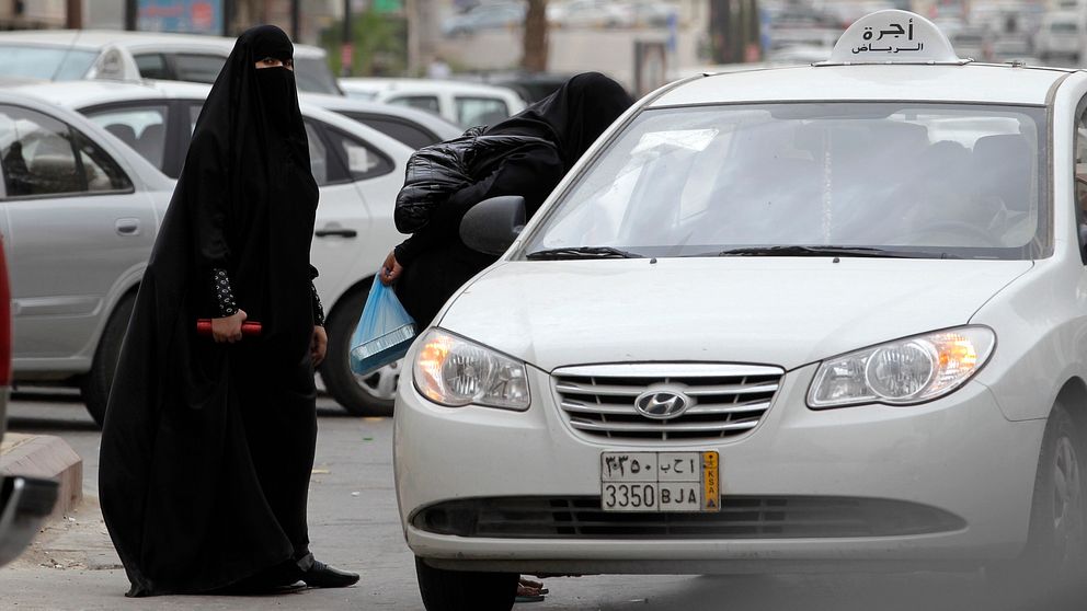 Två saudiska kvinnor står vid en bil.