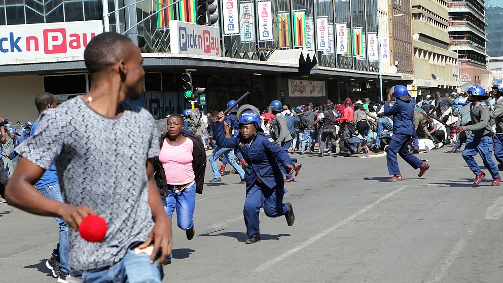 Polisen som jagar demonstranter i Zimbabwes huvudstad Harare under fredagen.