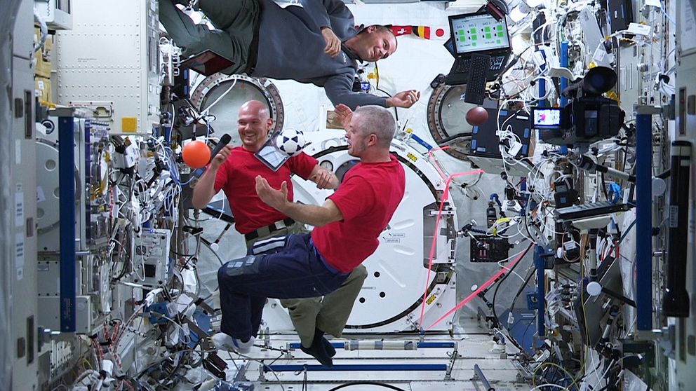 Tre astronauter svävar i luften inne på rymdstationen ISS.