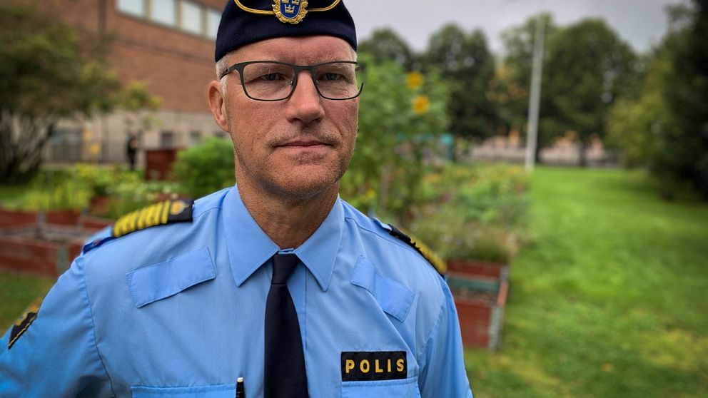 Polis står framför blomodlingar.