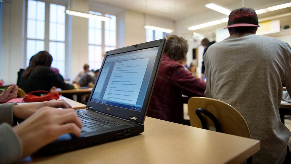 En elev sktiver på en dator i ett klassrum.