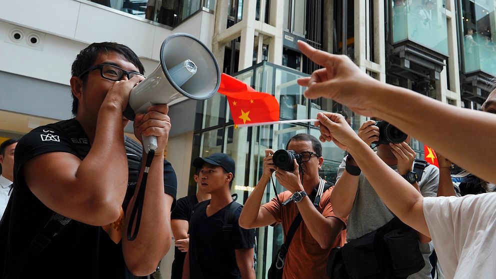 En demonstrant från proteströrelsen försöker göra sin röst hörd framför prokinesiska demonstranter i ett köpcentrum i Hongkong. Bild tagen fredag 13 september.