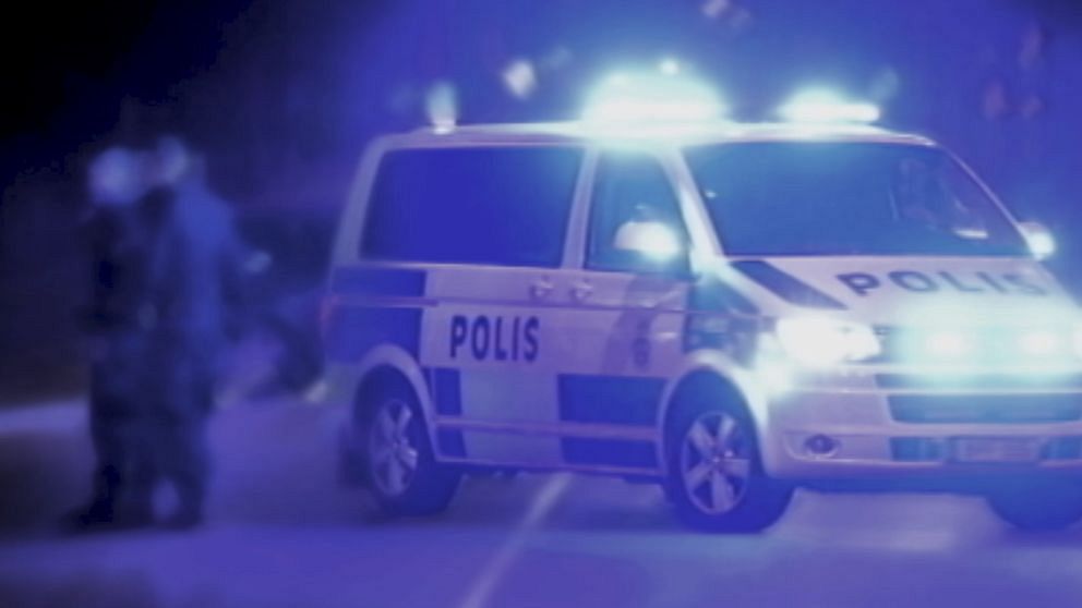 polisens piket-bil på gatan med blåljus på, suddiga figurer