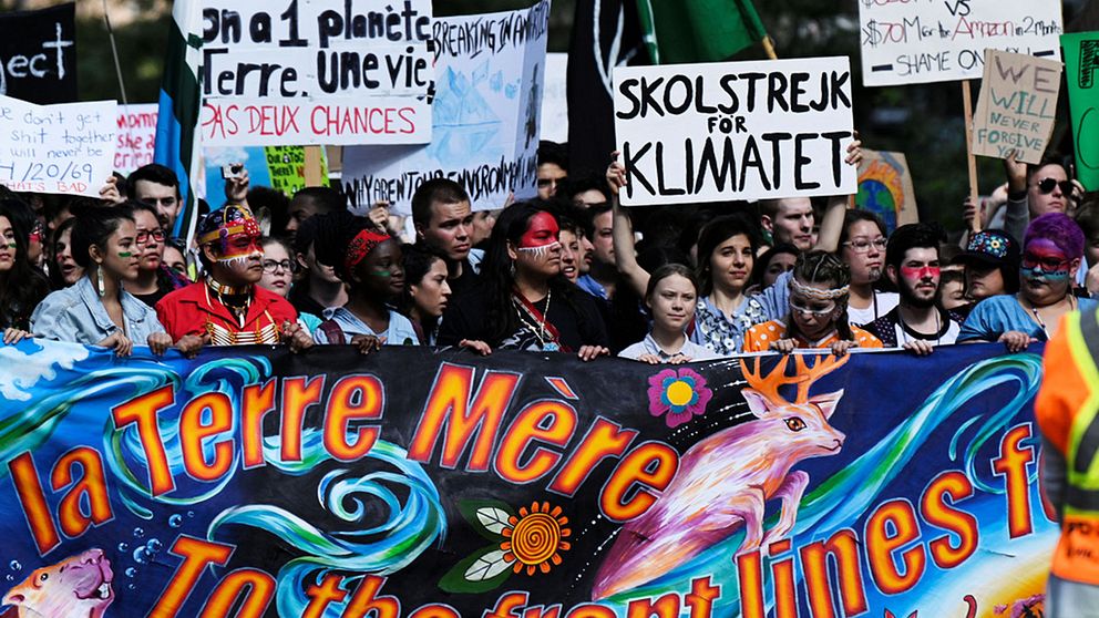 Greta Thunberg i en grupp med klimatdemonstranter som håller upp plakat