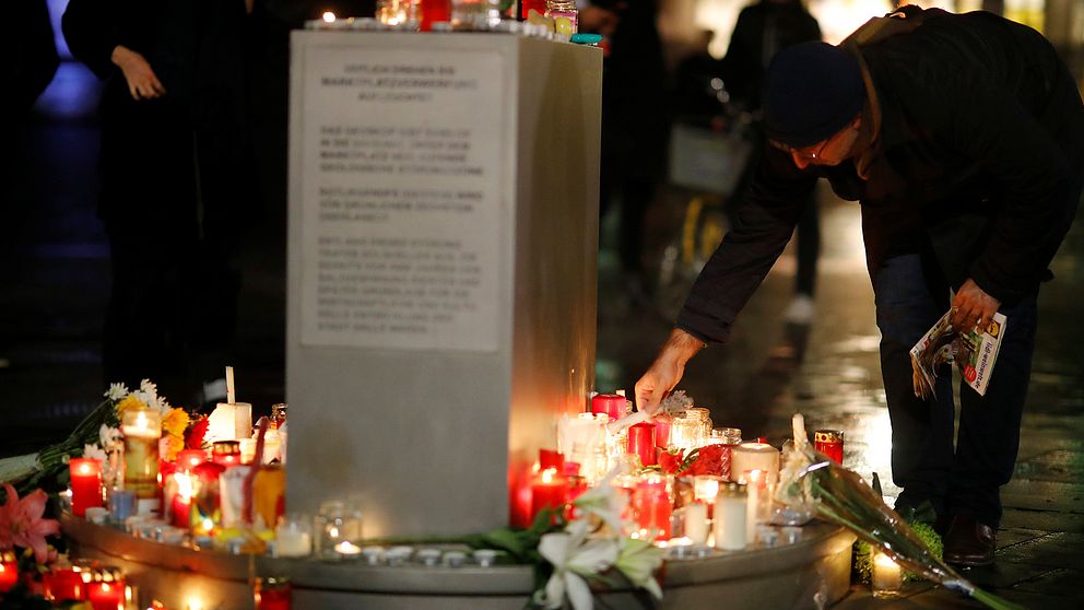 En person sätter ner ett ljus vid en manifestation för att hedra de som dog i attacken i Halle.