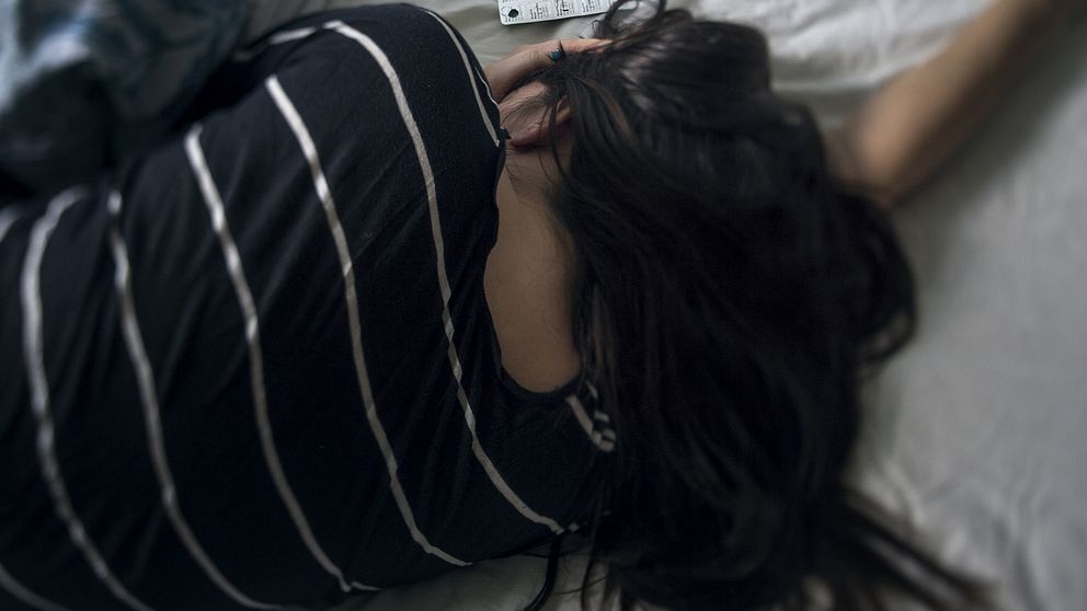 En ung kvinna ligger i en säng.