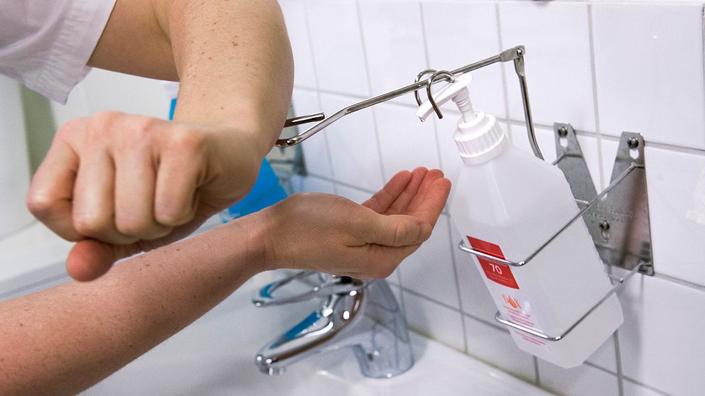 En vårdpersonals händer syns vid ett handfåt – tvättar sig med handsprit.